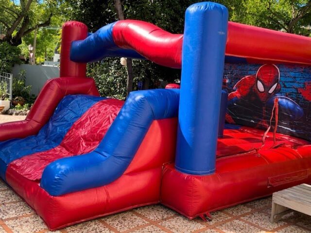 Castillo hinchable Spiderman XL rojo y azul con tobogán montado en un patio – Castillos Hinchables Madrid