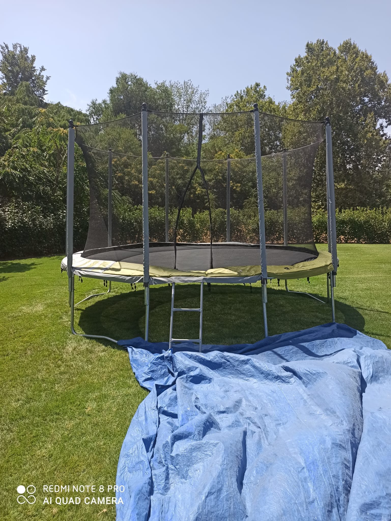 Cama elástica con red de seguridad montada en un jardín – Castillos Hinchables Madrid