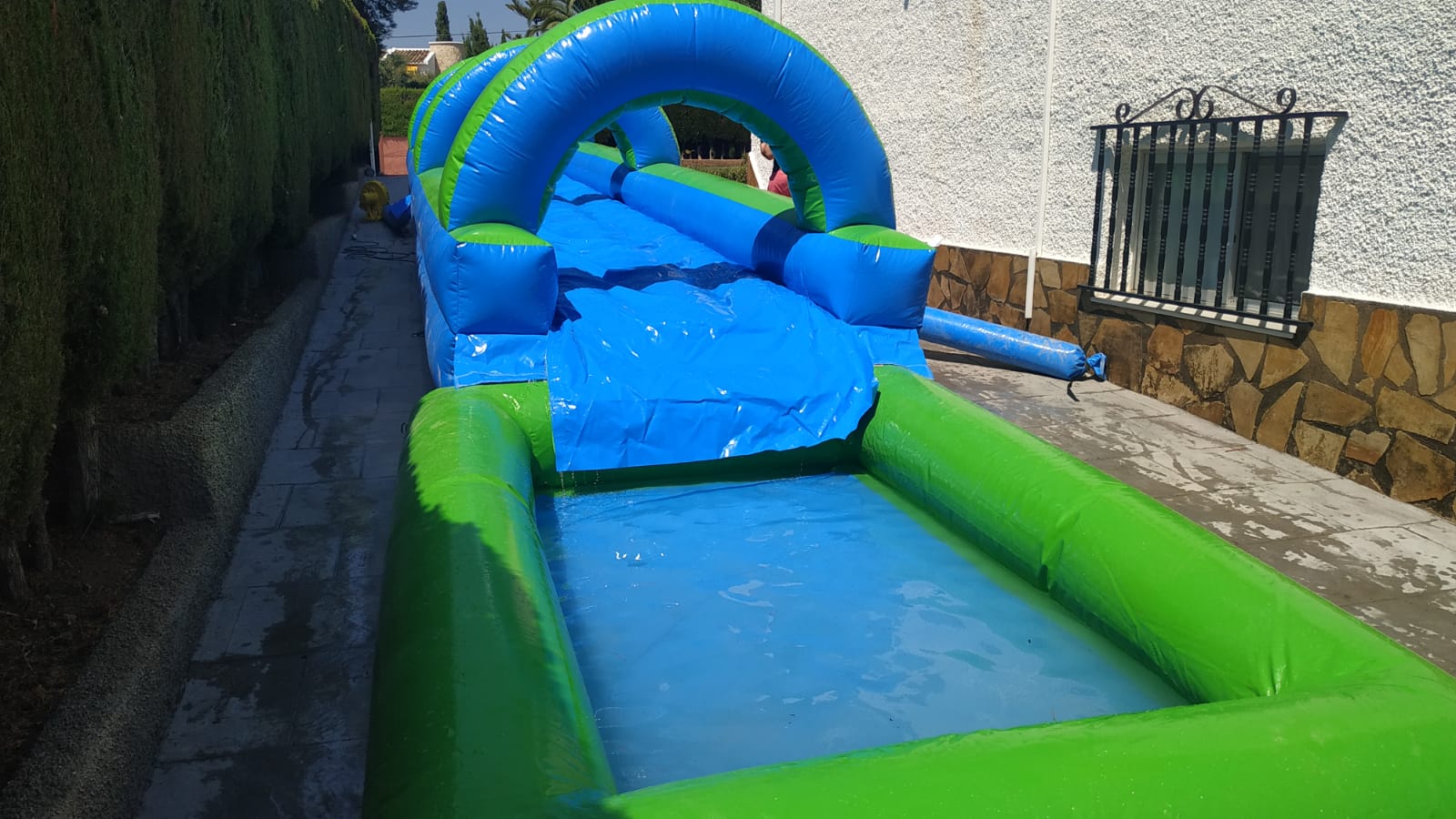 Deslizador hinchable acuático con piscina final montado en un jardín – Castillos Hinchables Madrid