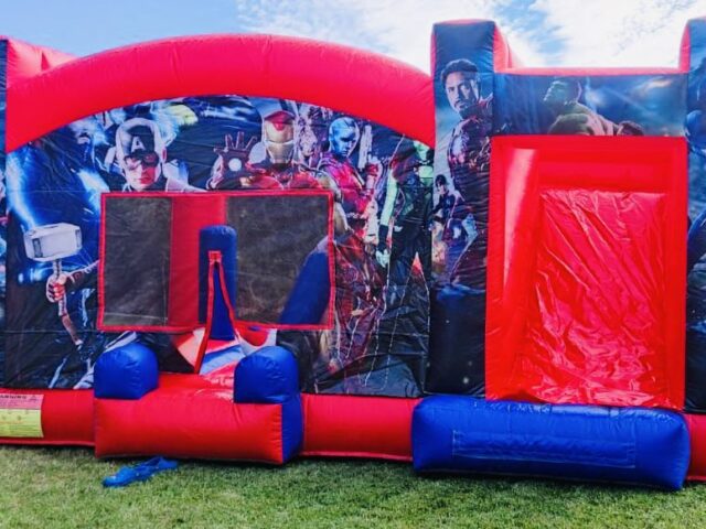 Castillo hinchable Superhéroes Liga de la Justicia XL rojo y azul con tobogán en un jardín – Castillos Hinchables Madrid